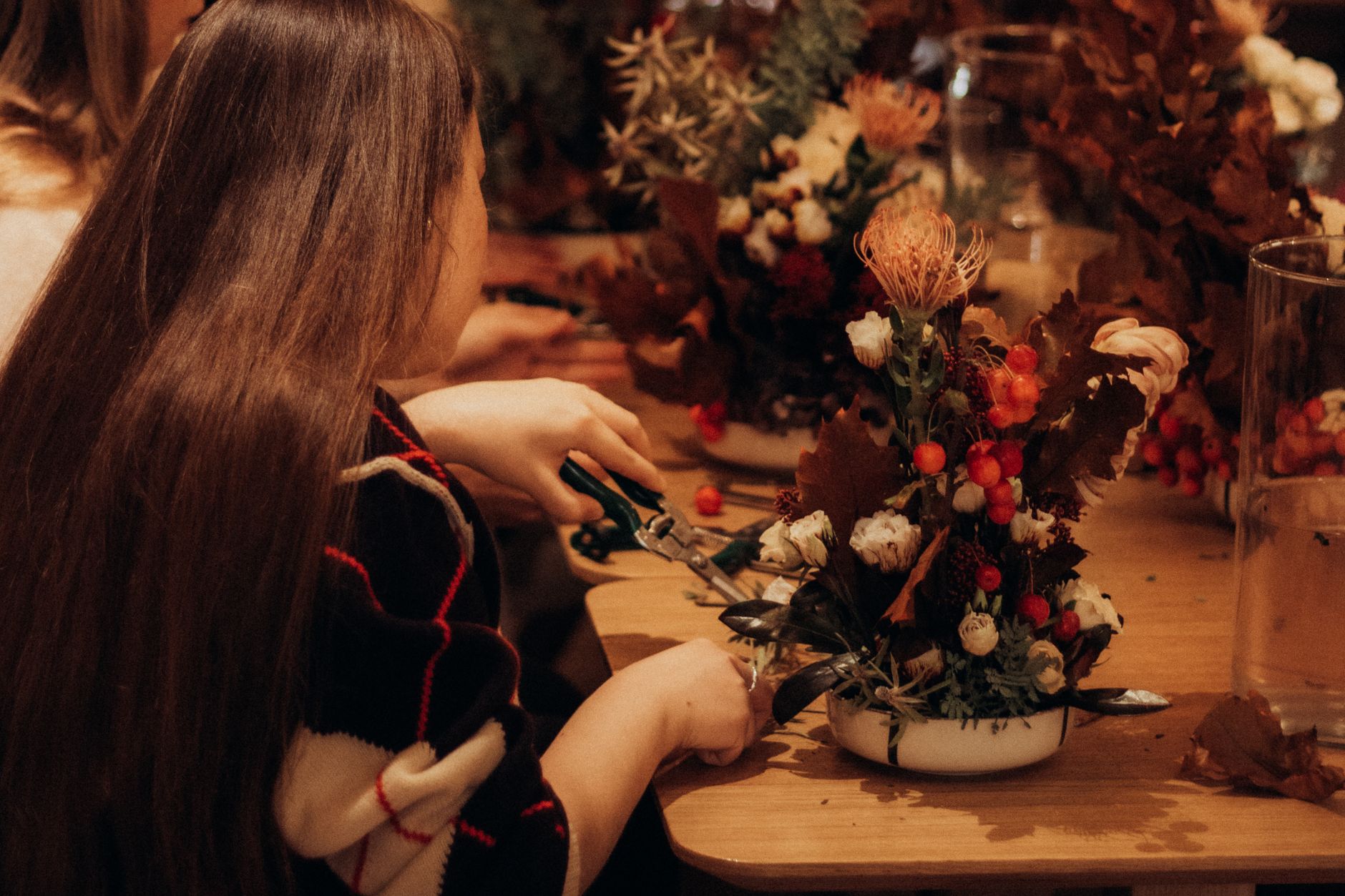 A woman crafting a beautiful autumn floral arrangement indoors.
