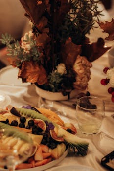 A warm and cozy autumn dinner table with a floral centerpiece and a fruit platter.