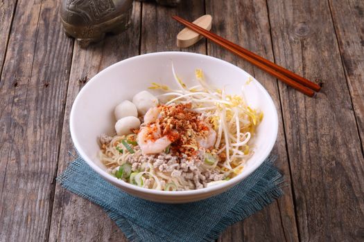 Tasty Asian noodle dish with shrimp, sprouts, and spices on a rustic table.