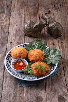 Delicious Thai fish cakes served with sweet chili sauce and decorative leaves.