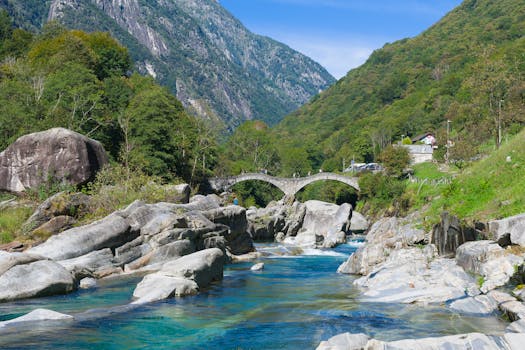 Picturesque view of Ponte dei Salti arch bridge over clear Verzasca River in Swiss Alps.