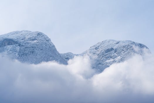 Stunning view of snow-covered alpine mountains with clouds drifting by in a serene winter landscape.