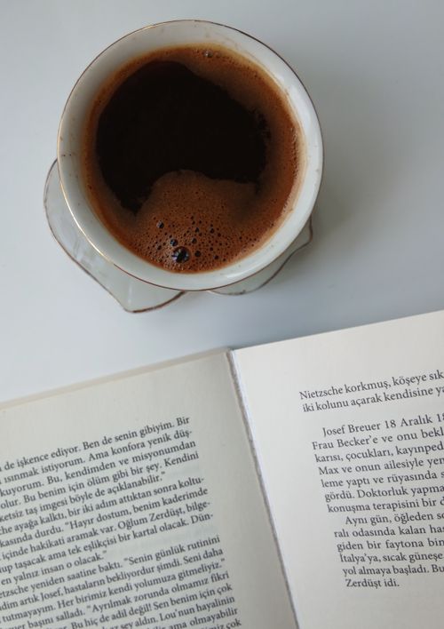 Free A coffee cup sits next to an open book with Turkish text on a white table, evoking a cozy reading moment. Stock Photo