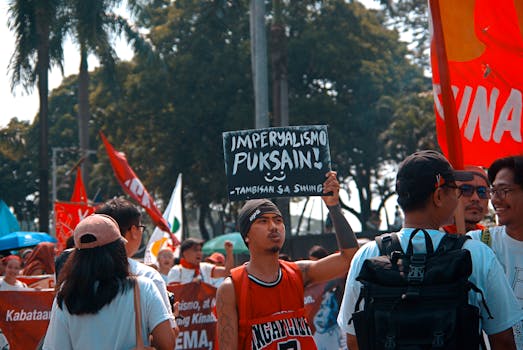 People participate in a demonstration, holding signs with messages against imperialism outdoors.