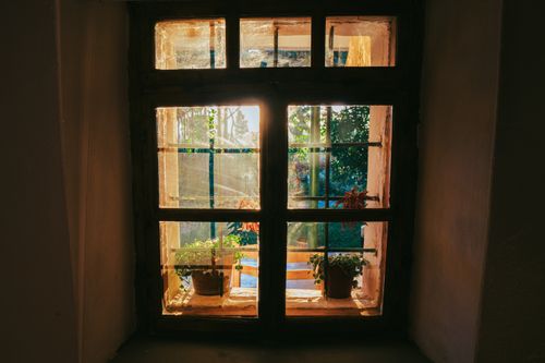 Free Sunset through a rustic window with potted plants in Fishtë, Albania captures serene village charm. Stock Photo
