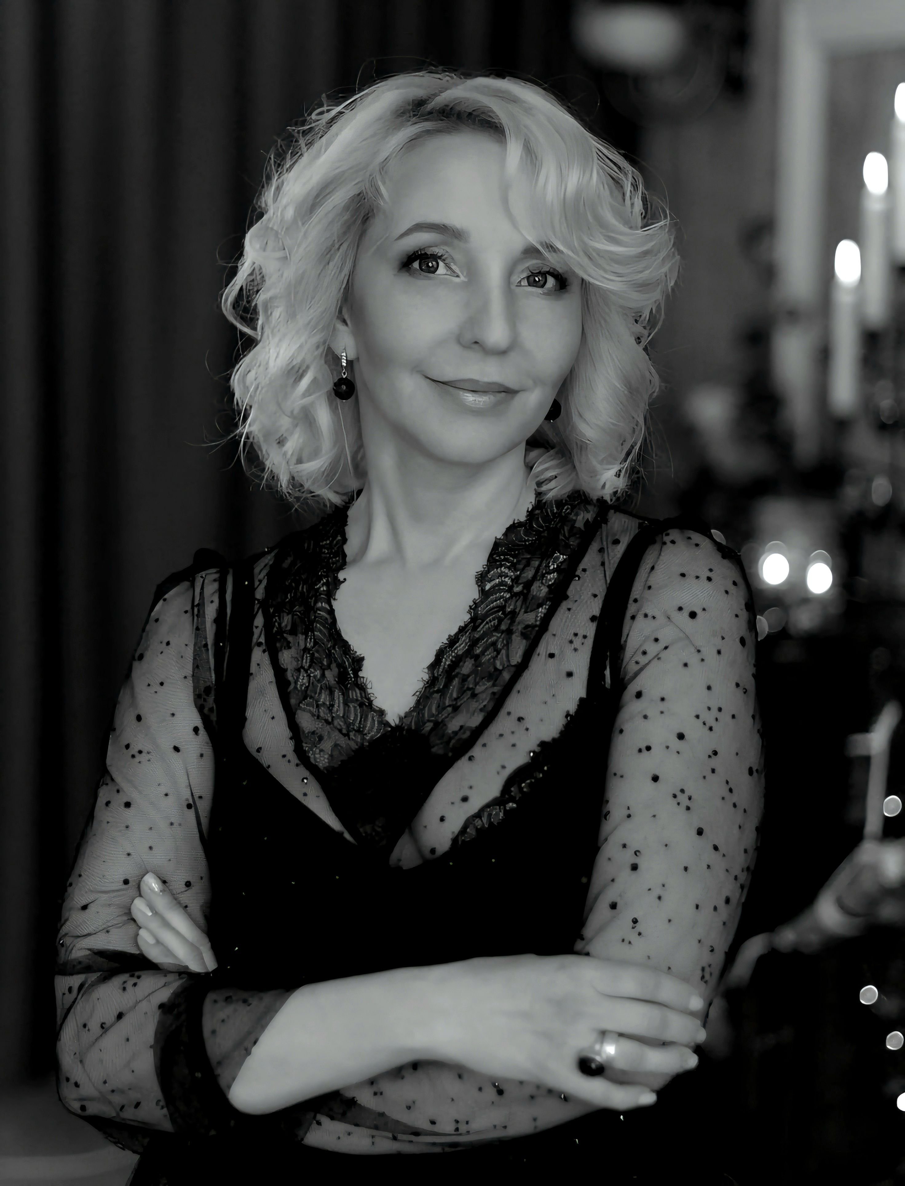 Sophisticated black and white portrait of a confident woman with crossed arms, wearing a delicate lace dress.
