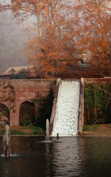 Peaceful view of a waterfall surrounded by autumn foliage in Srinagar, perfect for nature enthusiasts.