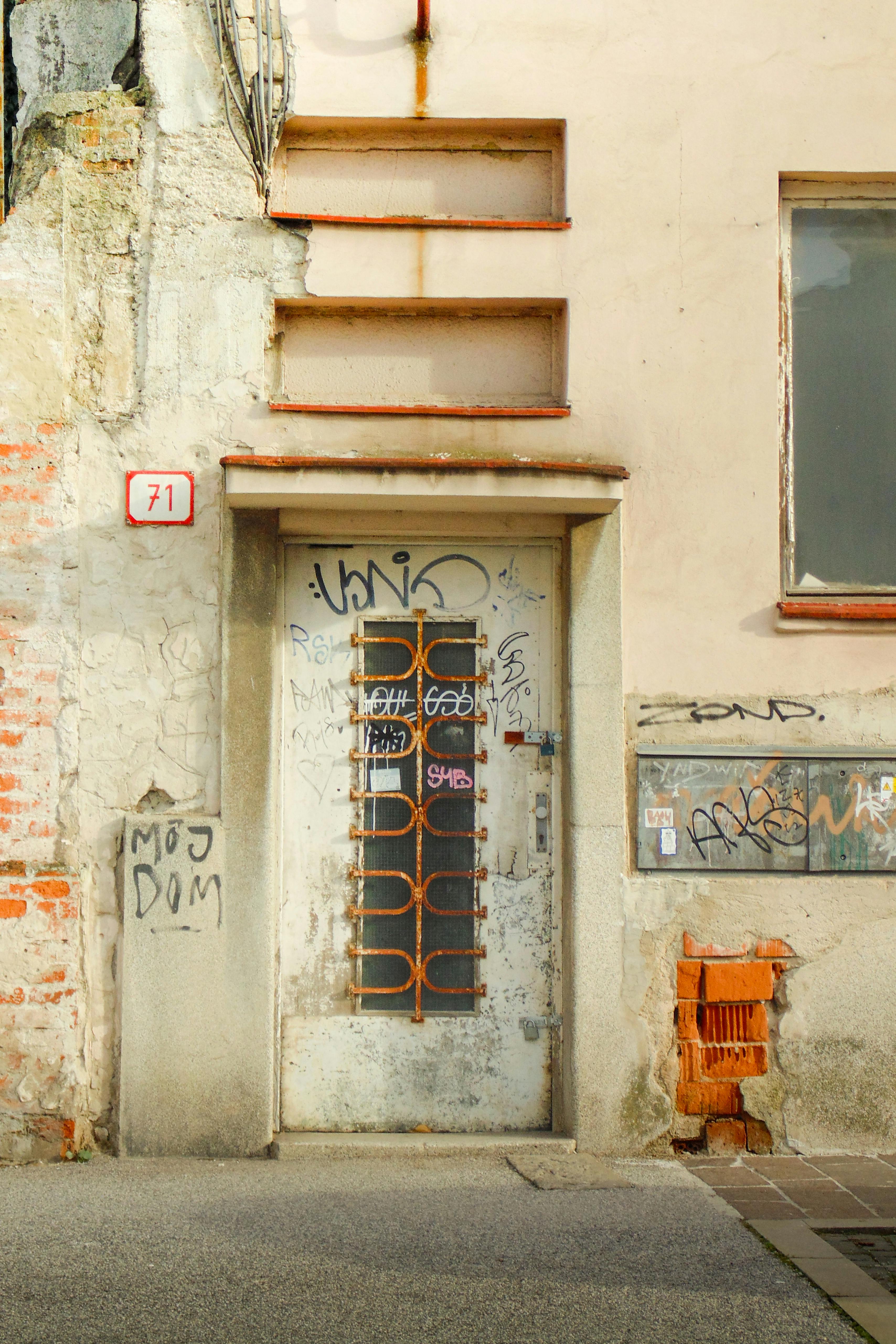 A weathered building facade with graffiti and vintage door in Slovakia, showcasing urban decay.