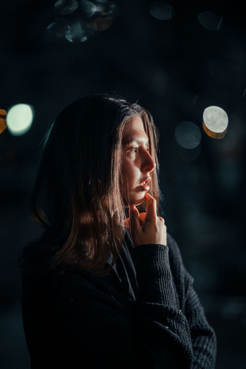 Portrait of a woman in deep thought at night with soft bokeh lights