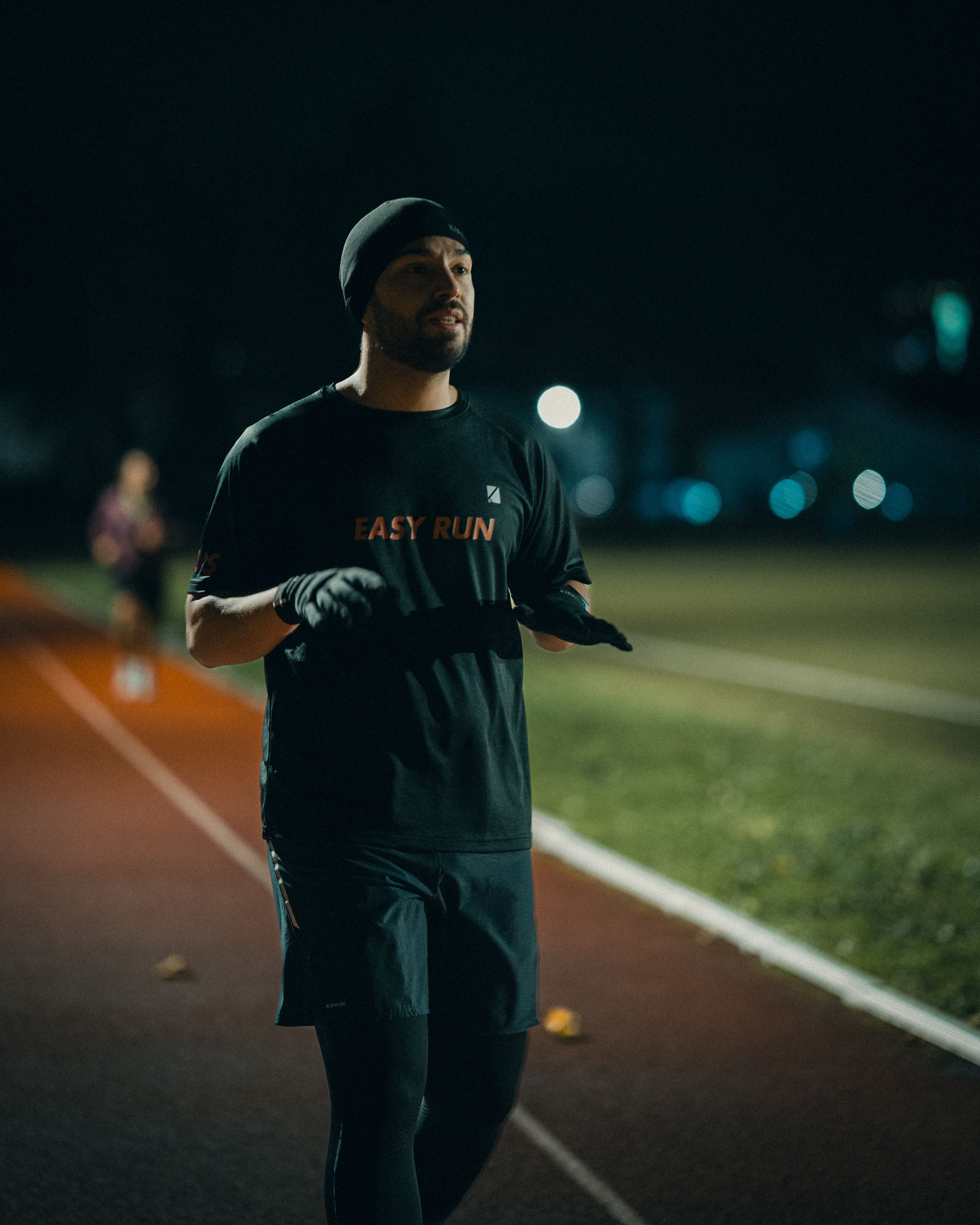 Man jogging on a track at night with a focus on fitness and endurance.