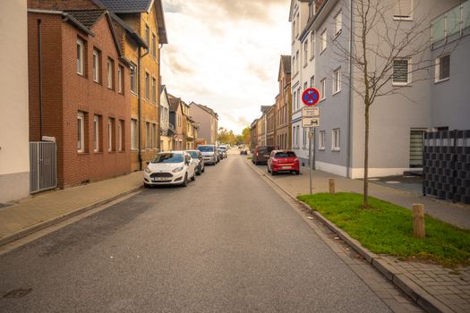 A serene neighborhood street scene in fall, showcasing German architecture and autumn foliage.