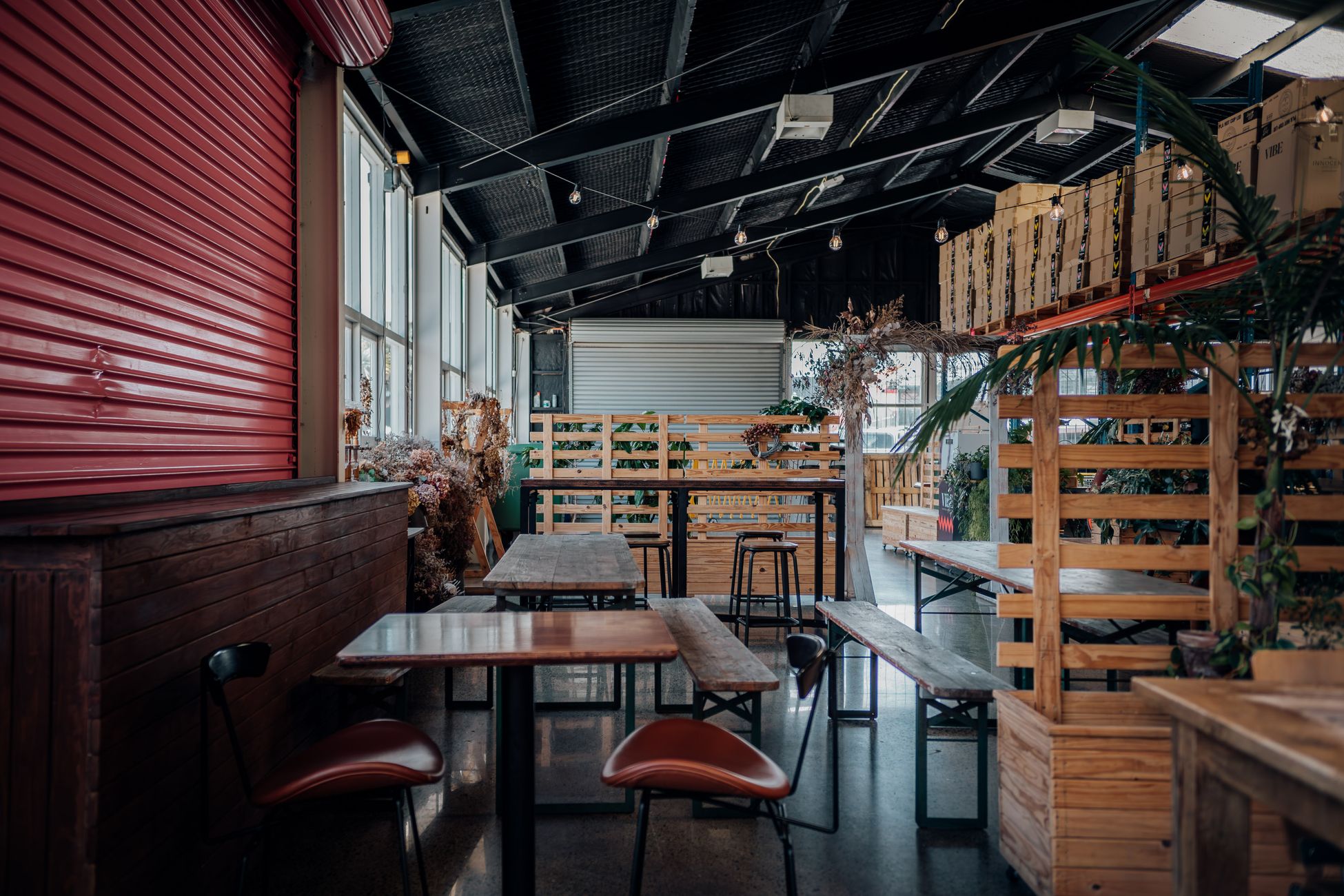 Cozy industrial-style cafeteria with wooden seating, plants, and modern lighting.