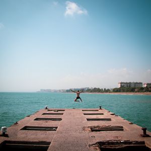 Person leaping off a pier into the blue sea — photo by Ahmet Camli on Pexels