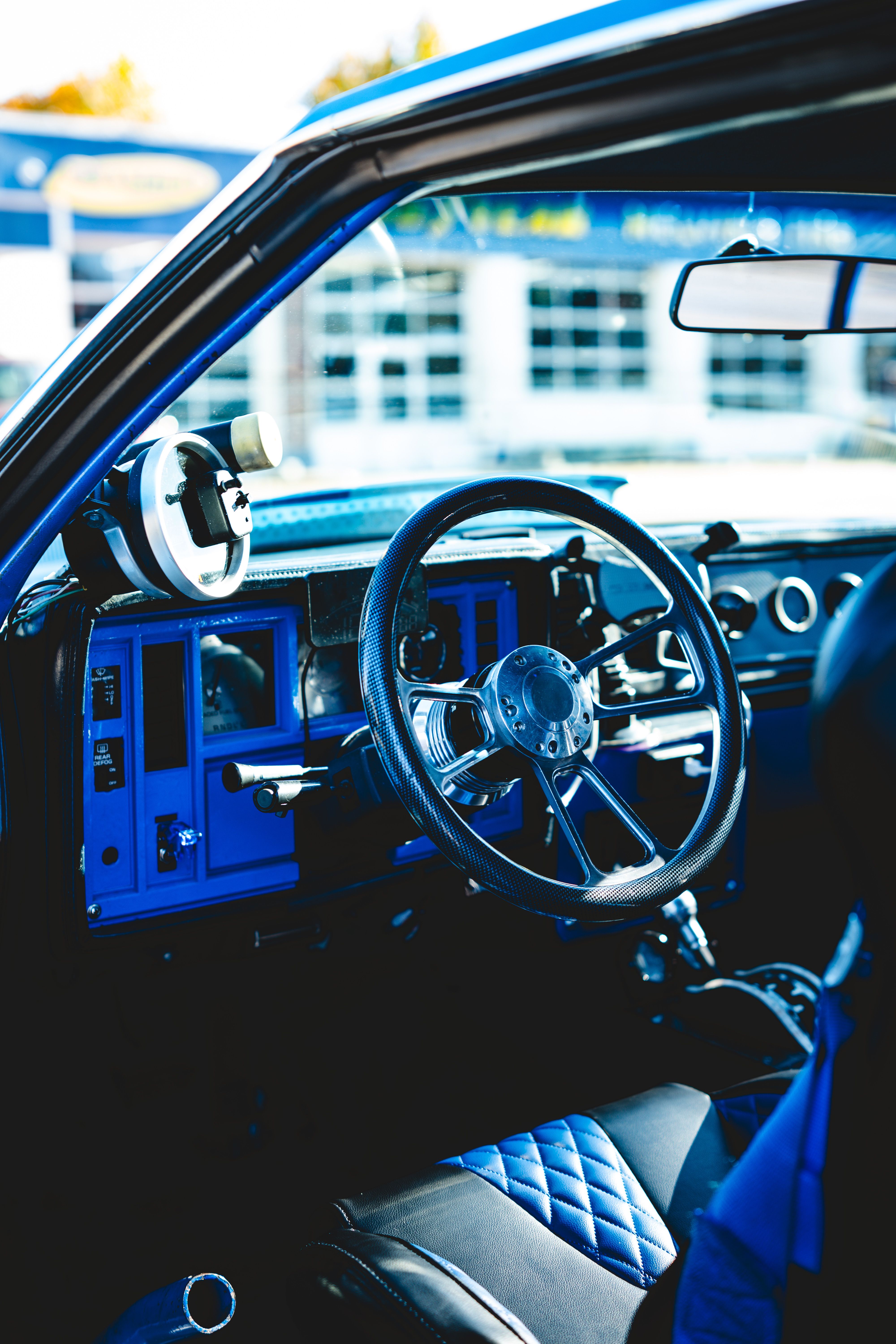 Close-up of a blue vintage car interior with stylish details and steering wheel.