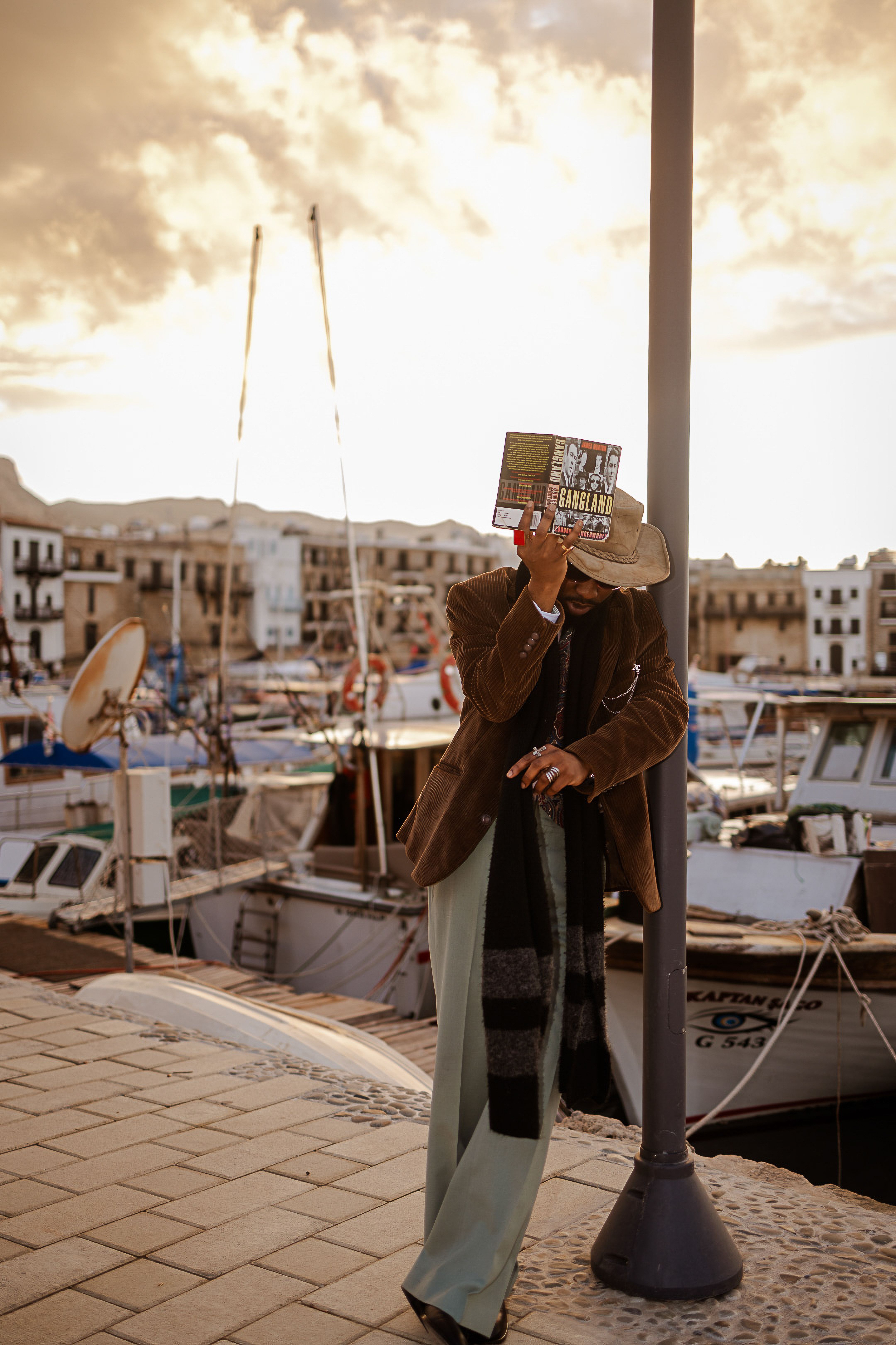 Portrait of a stylish man by the marina, showcasing casual elegance with accessories.