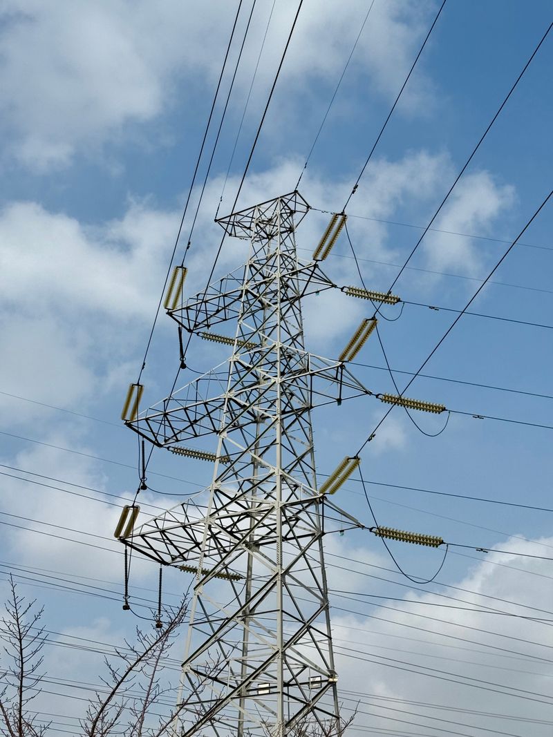 High-voltage power transmission tower against a bright blue sky