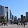 Pedestrians cross a busy intersection in Seoul's central business district, surrounded by modern corporate skyscrapers.