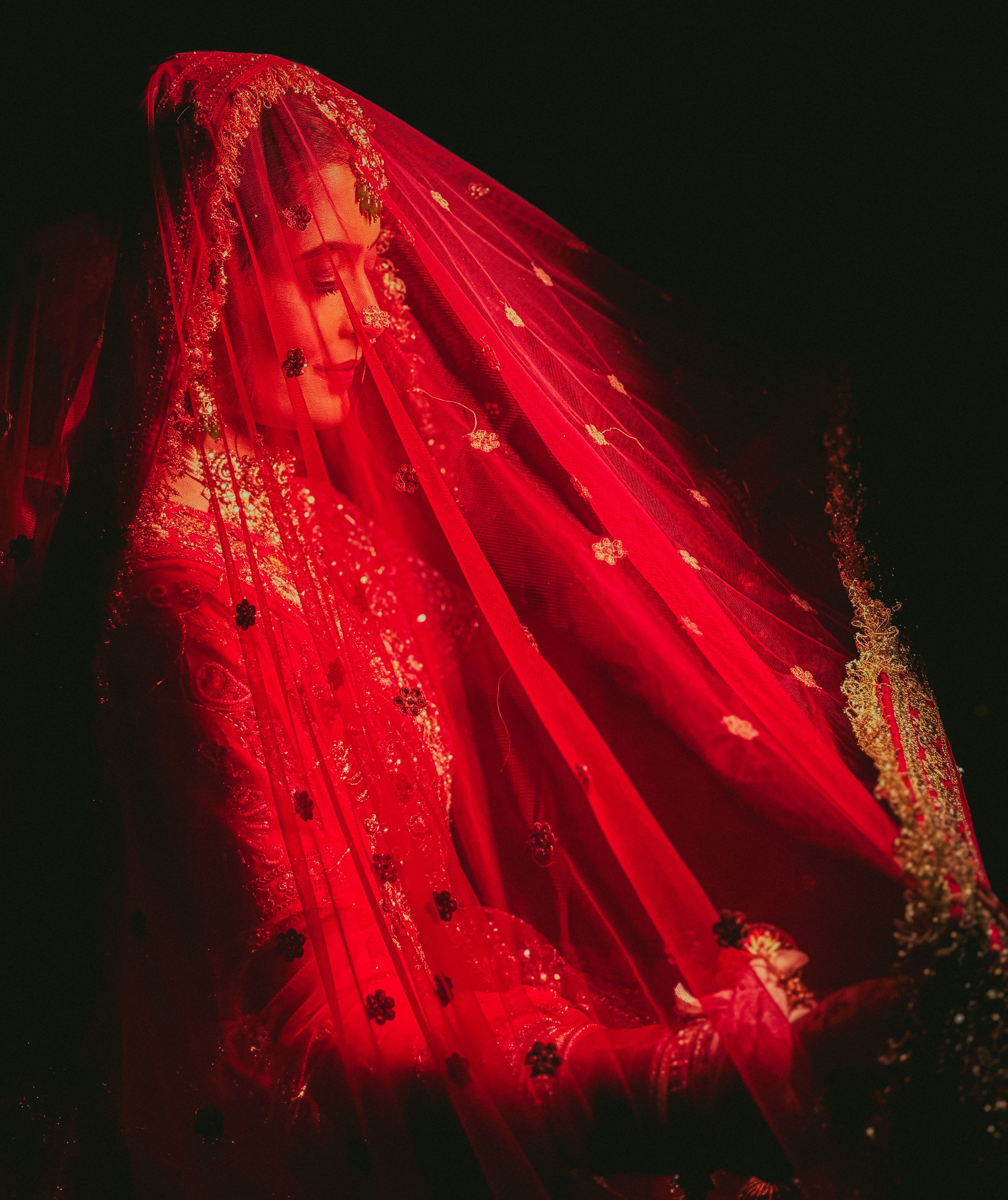 Portrait of a bride wearing a beautiful red veil, capturing traditional elegance and grace.