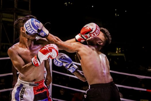 Exciting boxing match with two fighters exchanging punches in a well-lit boxing ring at night.