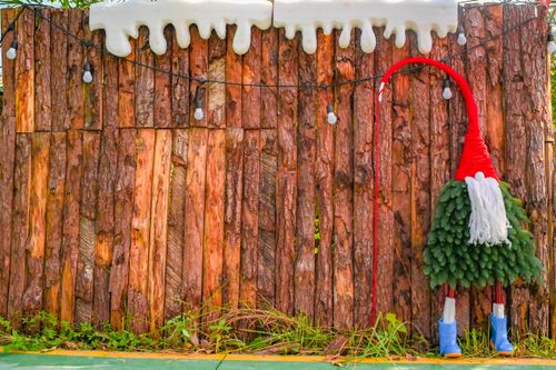 Free Colorful gnome decoration on a rustic wooden fence, ideal for festive and holiday themes. Stock Photo
