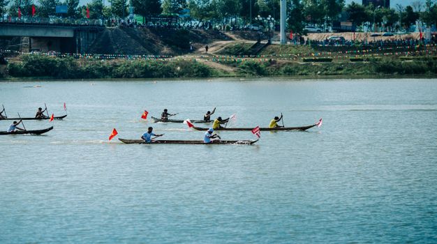 Wooden boats in a vibrant race across a river in Kon Tum, Vietnam, showcasing cultural heritage.