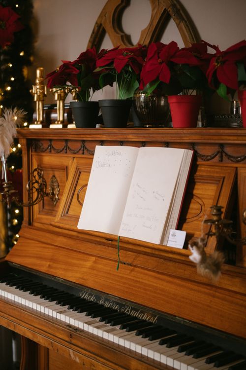 Free Wooden piano with open sheet music surrounded by poinsettias and Christmas decorations. Stock Photo
