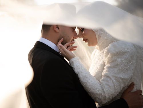 Free A close-up view of a bride and groom sharing an intimate moment under a delicate veil. Stock Photo