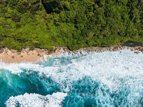 Free Stunning aerial view of Bali's coastline, vibrant ocean and lush greenery. Stock Photo