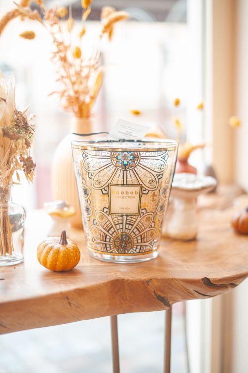 Free Decorative Baobab candle with intricate design, alongside autumnal decor on a wooden table. Stock Photo