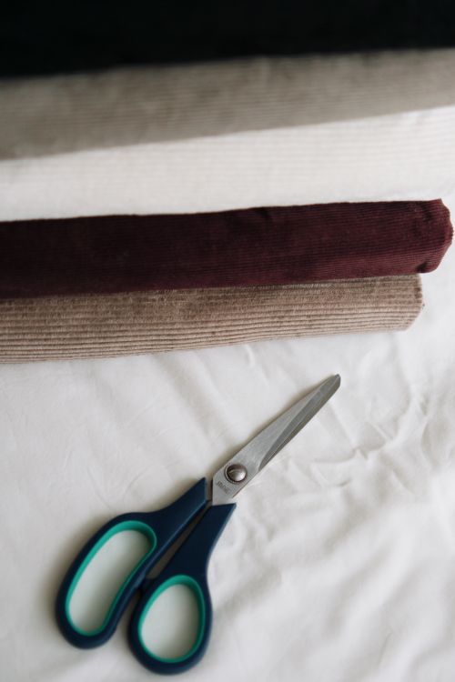 Free Colorful fabric rolls and scissors on a white surface, perfect for sewing or crafting projects. Stock Photo