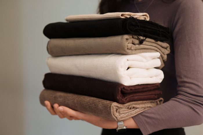 Stack of folded neutral-toned fabrics held in two hands — photo by Berna on Pexels