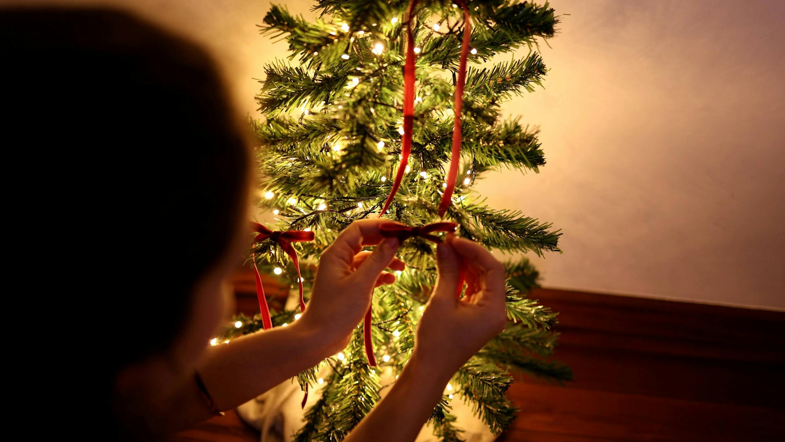 Decorating a Christmas Tree with Red Ribbons · Free Stock Photo