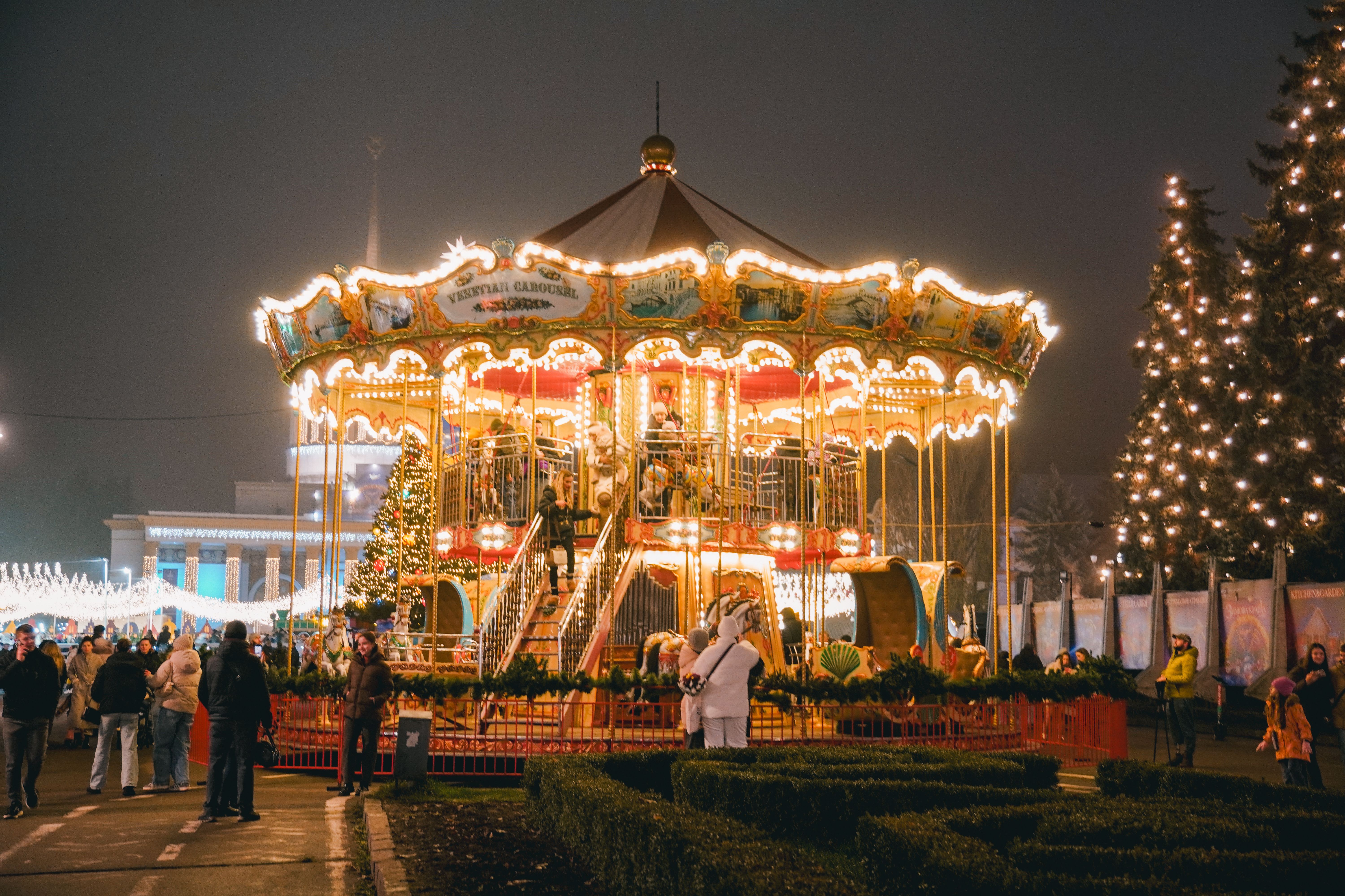 A vibrant Christmas carousel in Kyiv, Ukraine at night, surrounded by people enjoying the holiday spirit. — Trójmiasto