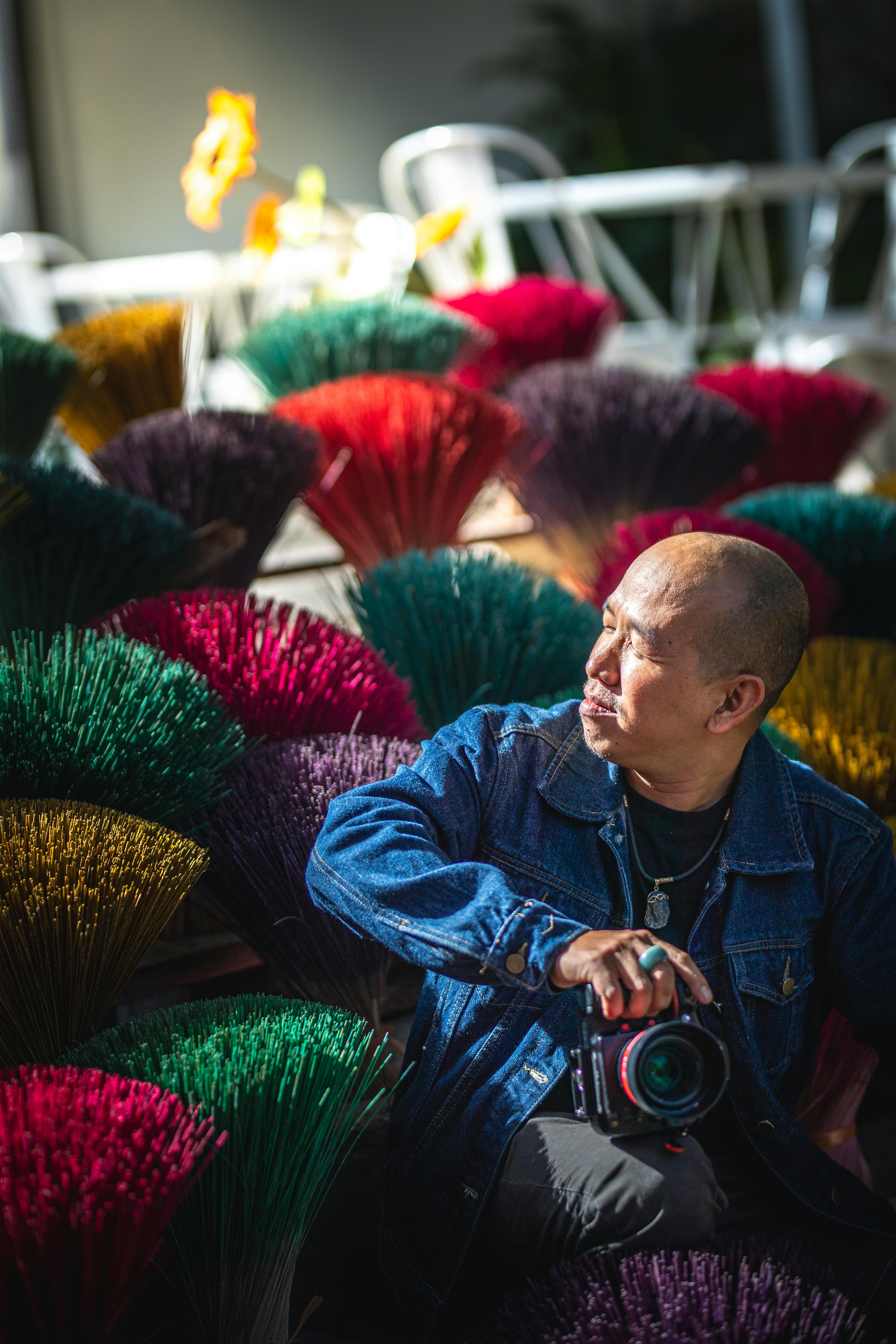 A photographer surrounded by colorful incense sticks capturing the moment.