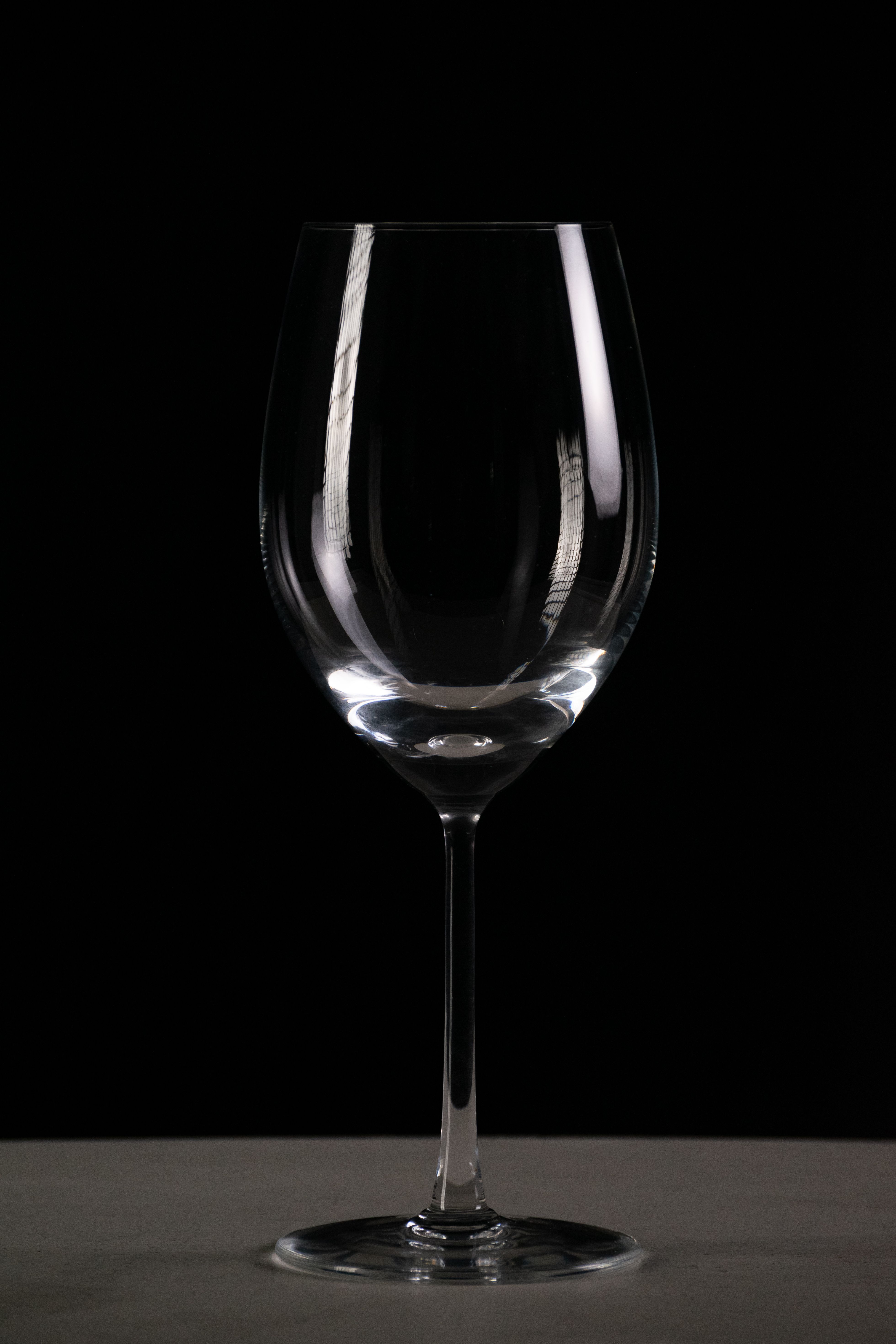 Minimalist photo of a wine glass against a dark backdrop, perfect for elegant themes.