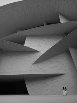 Monochrome image of modern architecture in Doha with two people, exploring geometric design.