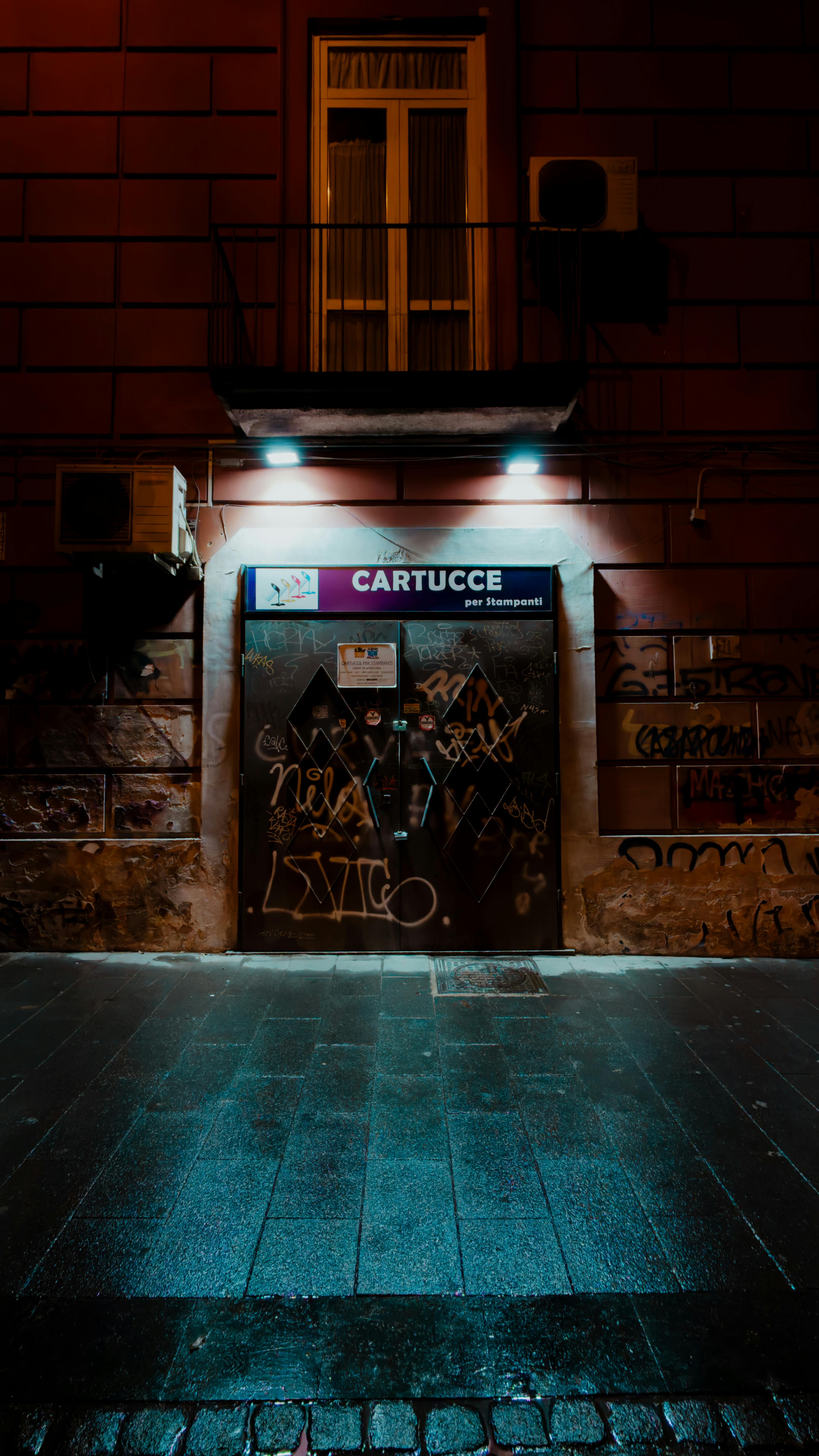 Kostenlos Nachts eine mit Graffiti bedeckte Ladenfront, gedämpftes Straßenlicht und urbanes Flair. Stock-Foto