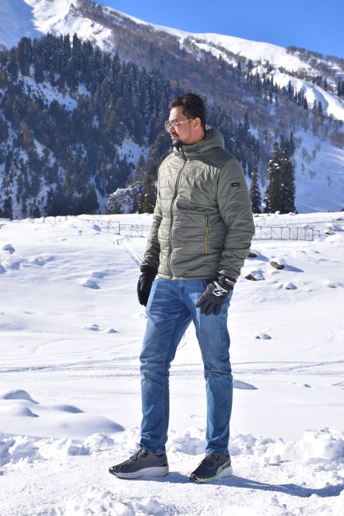 Free Portrait of a man in winter attire standing in a snowy mountain landscape. Stock Photo