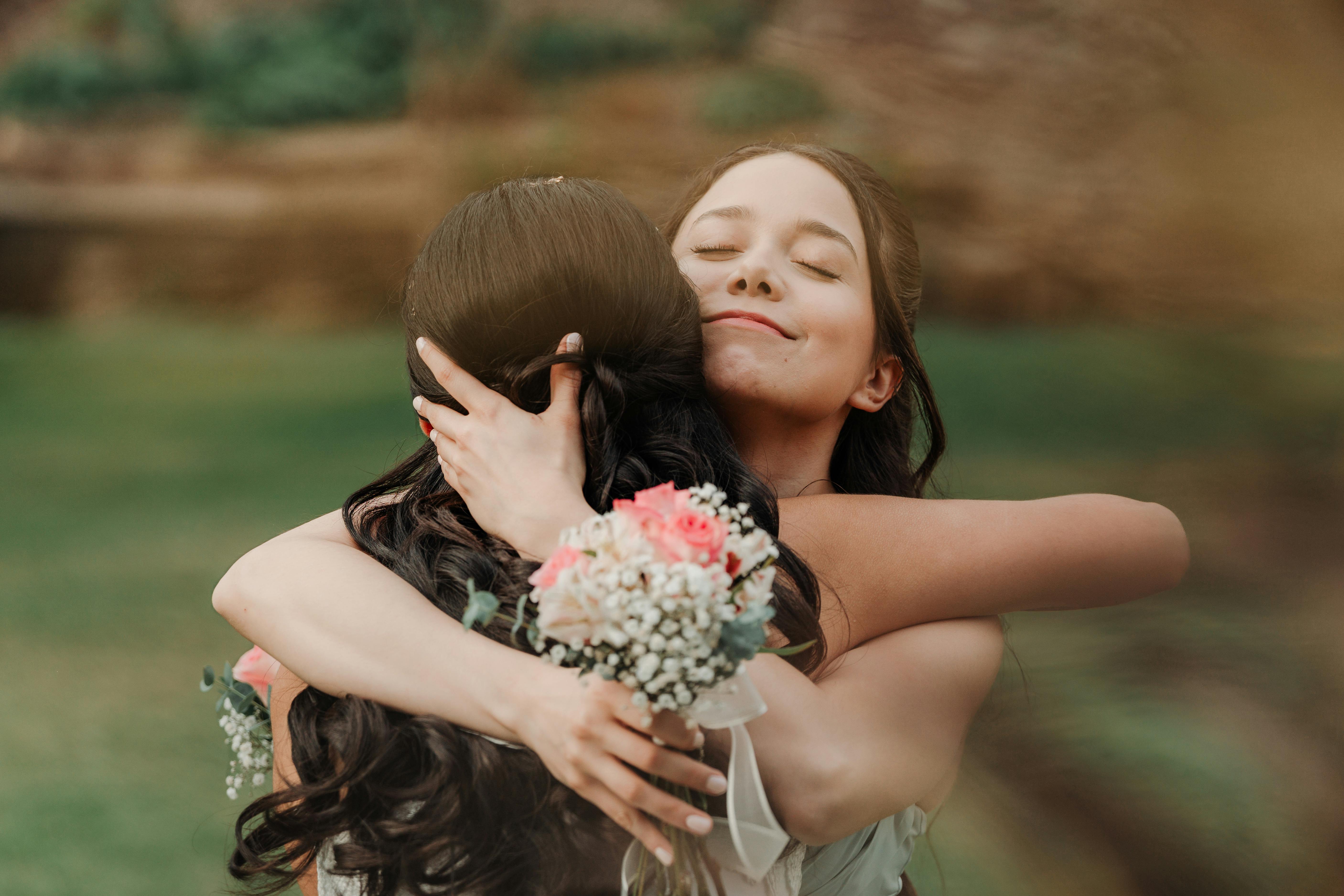 Heartfelt embrace between two women at an outdoor wedding, symbolizing love and friendship.