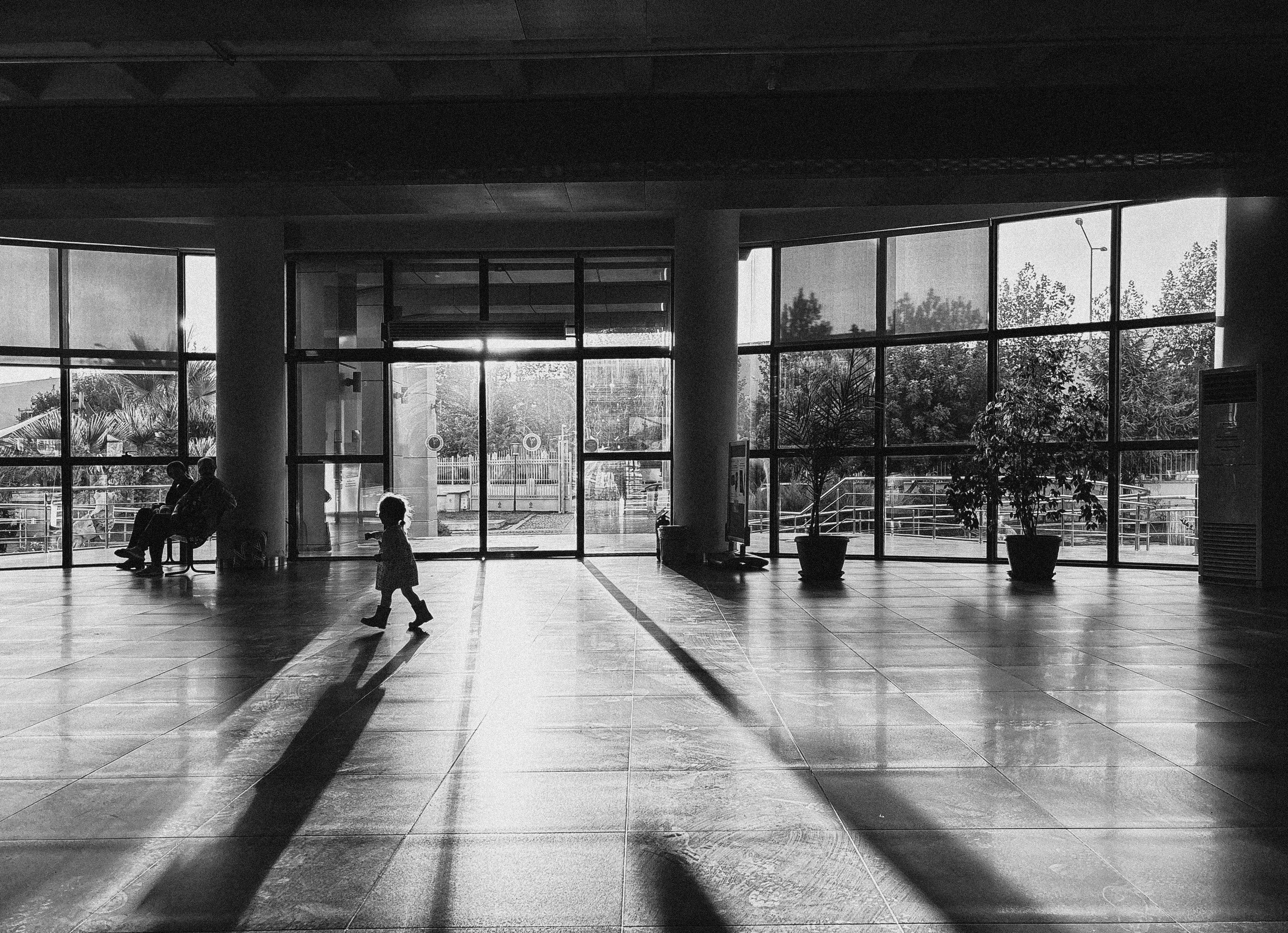 A modern church building with families entering, sunlight streaming through large glass windows