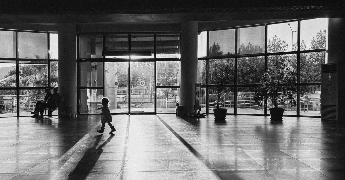 A modern church building with families entering, sunlight streaming through large glass windows