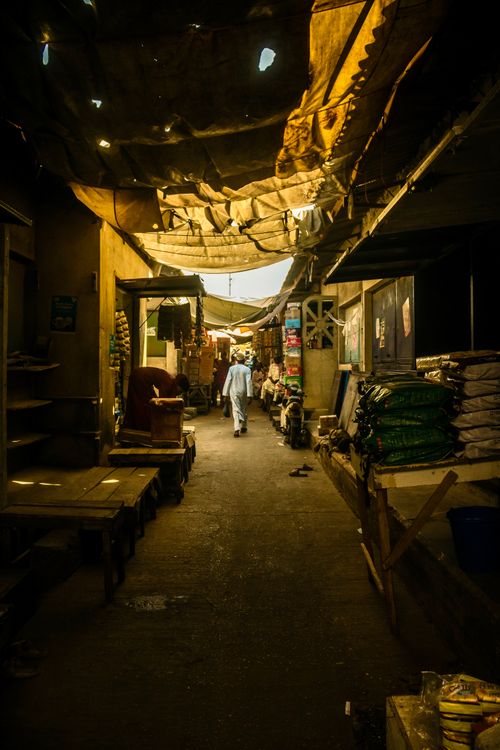 Free A narrow, rustic market alleyway with natural light filtering through the roof, creating a warm ambiance. Stock Photo