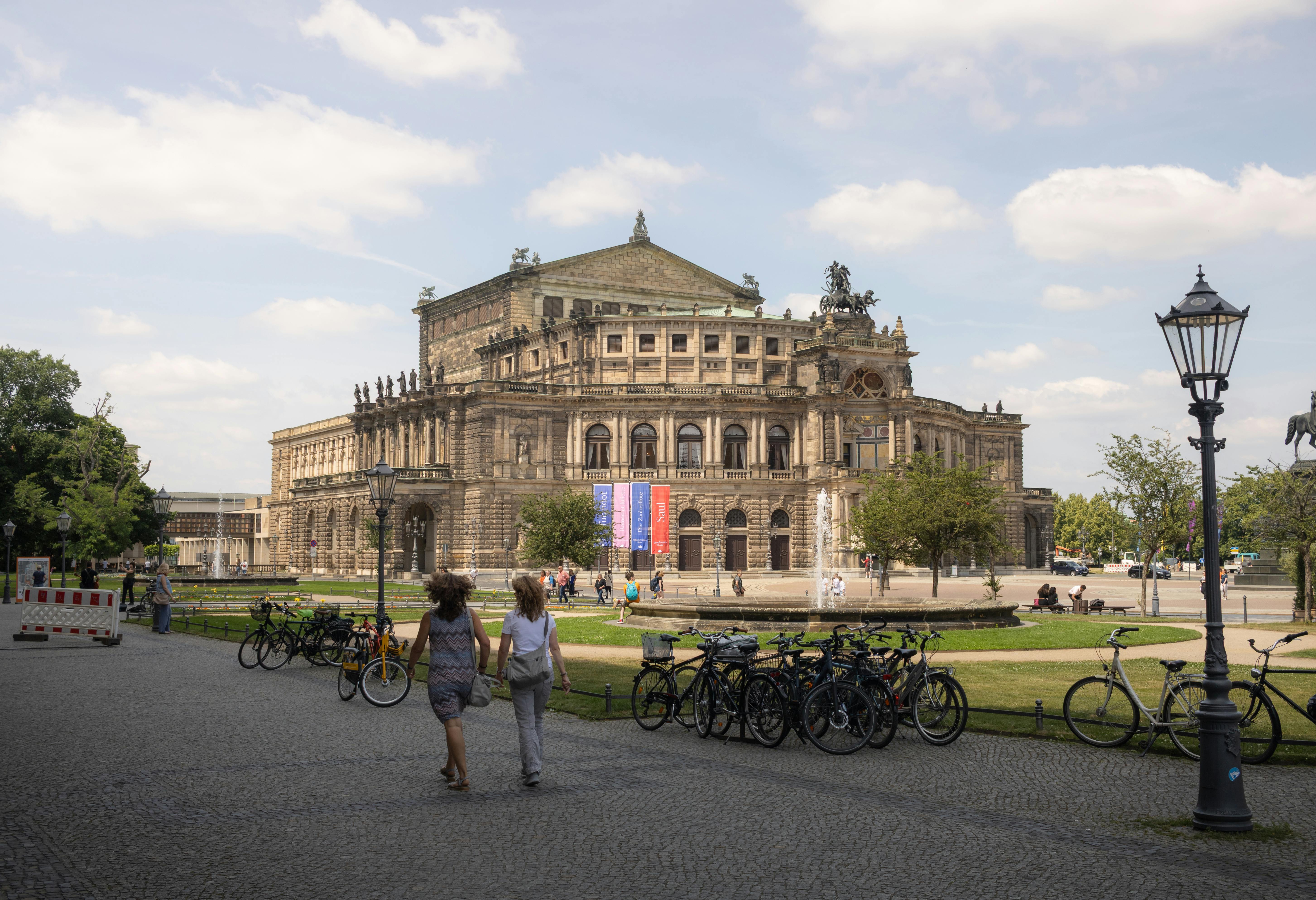 Ücretsiz Dresden'deki ikonik Semperoper'in berrak gökyüzünün altında insanlarla ve bisikletlerle birlikte görünümü. Stok Fotoğraflar