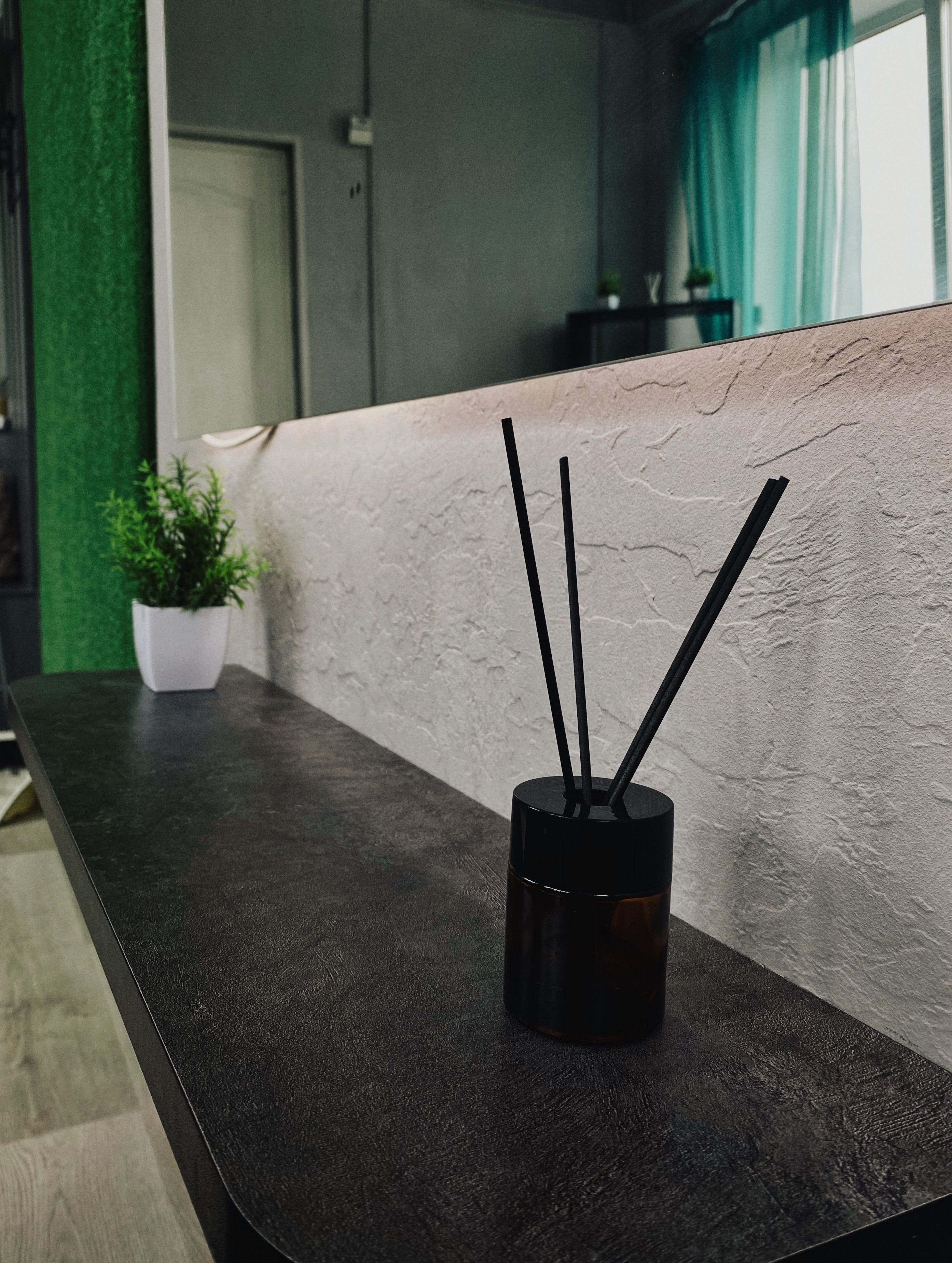Interior contemporâneo com um difusor de varetas sobre uma mesa elegante e decoração sofisticada.