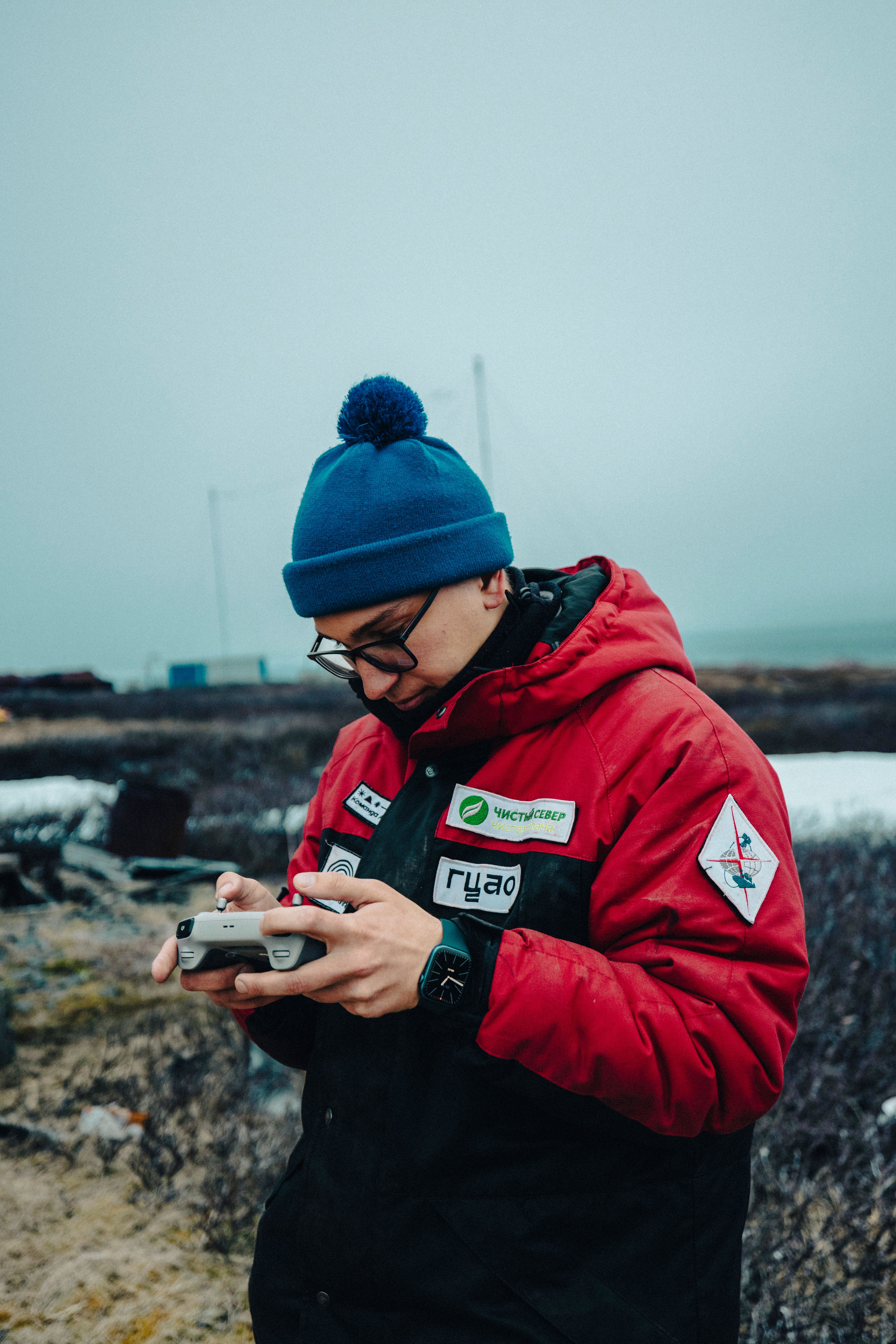 Individual in winter attire operating a drone in a chilly outdoor setting.