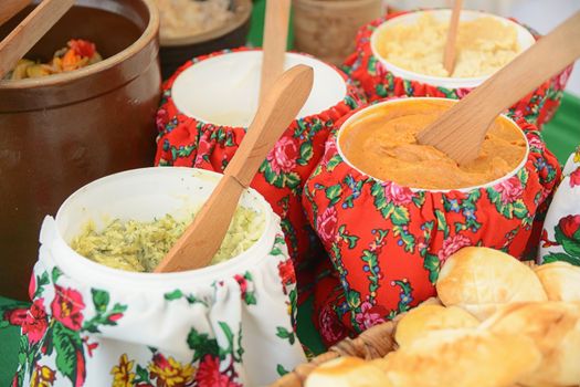 A vibrant display of traditional dishes with wooden spoons in colorful floral cloth-covered pots.