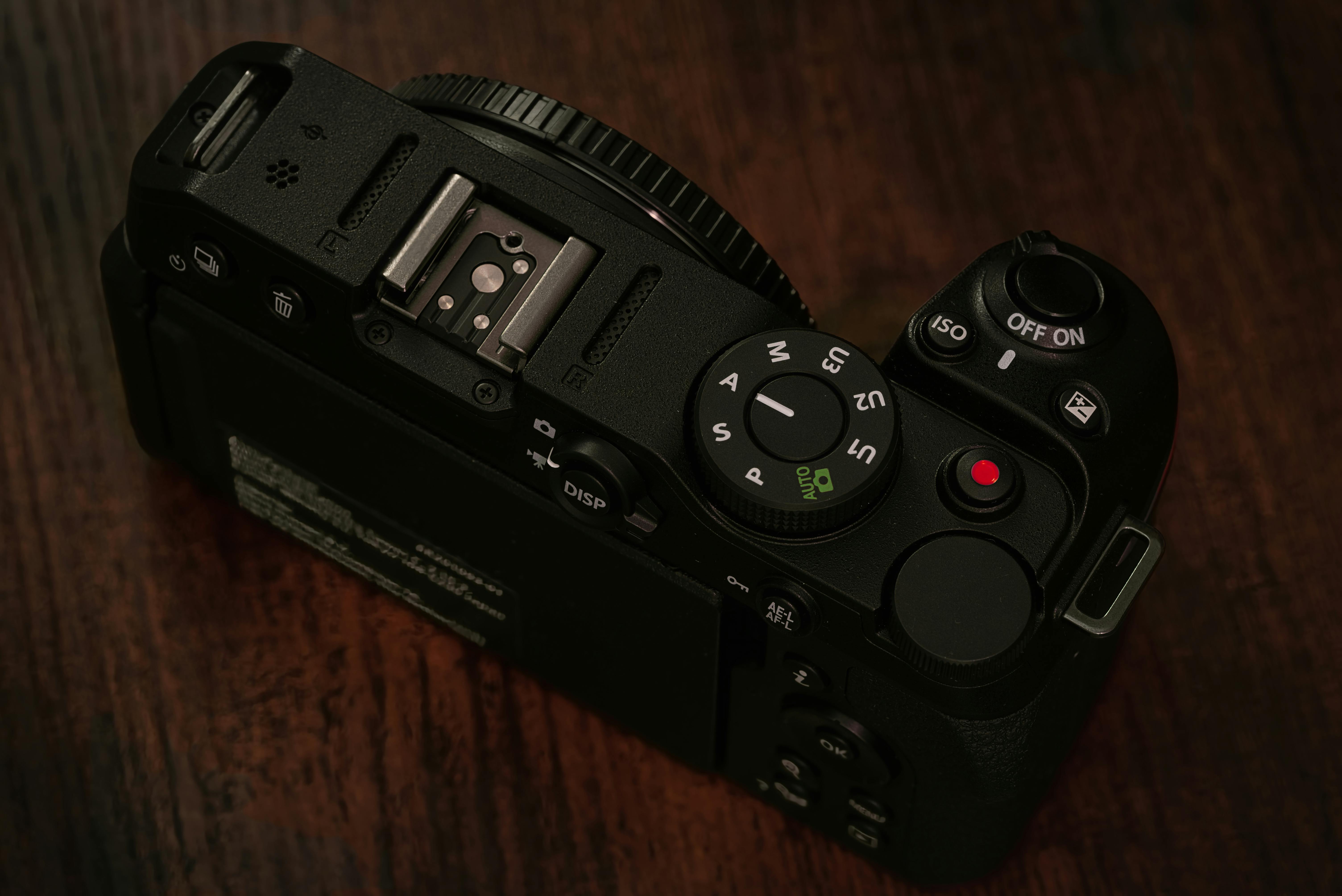 Free Close-up shot of a black DSLR camera from above on a dark wooden background, showcasing controls. Stock Photo