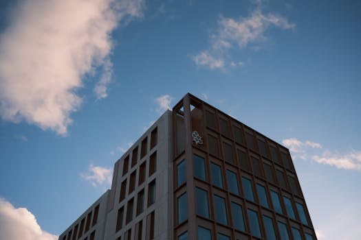 Contemporary building facade with clear sky and clouds backdrop.