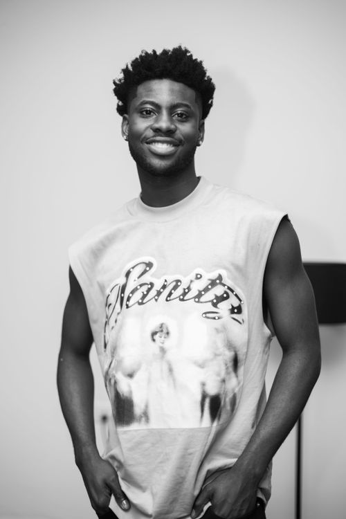 Free Striking black and white portrait of a smiling man in a graphic tee, captured indoors with a casual vibe. Stock Photo