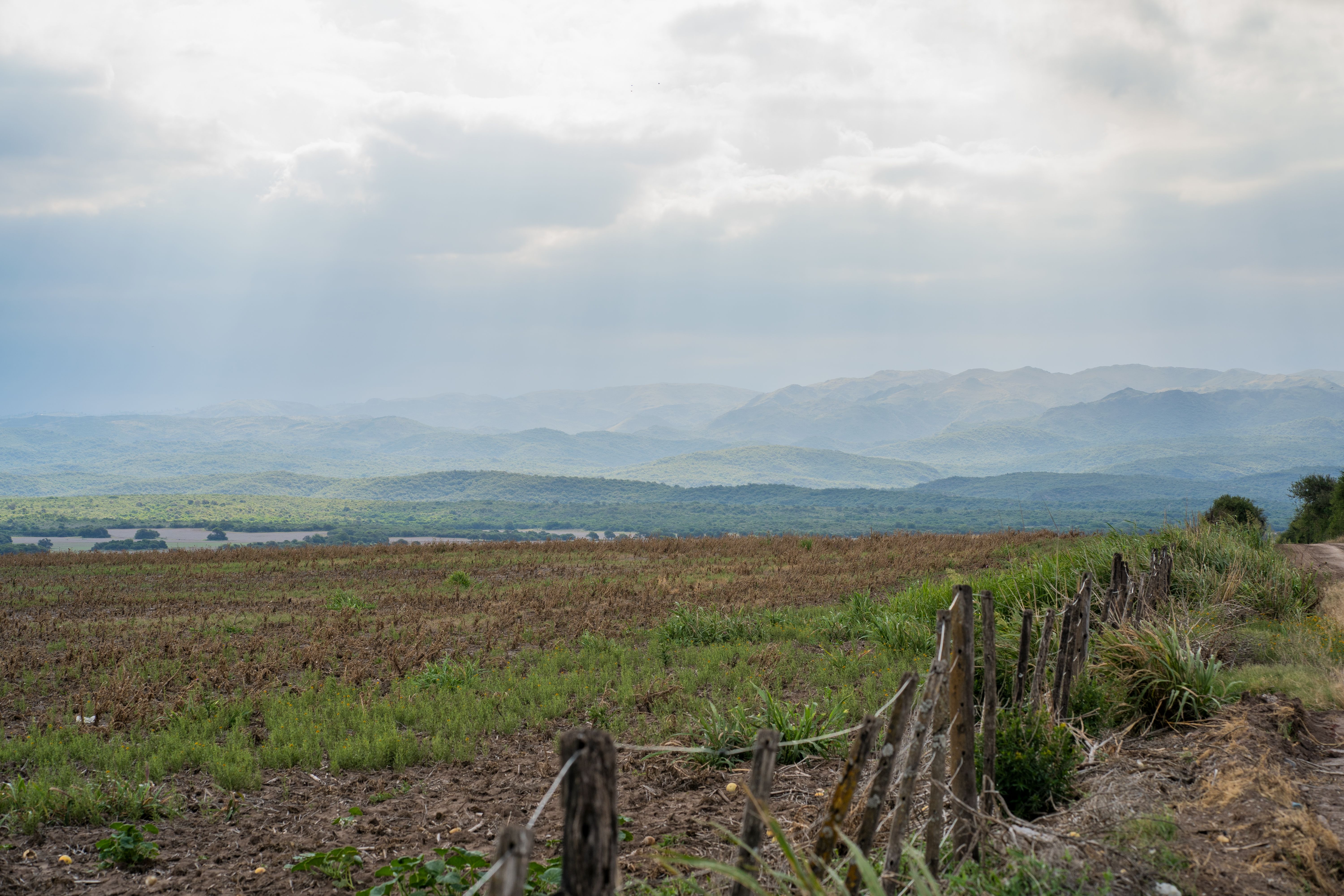 Fotomural Vista panorámica de campos y montañas bajo un cielo nublado en Córdoba, Argentina.